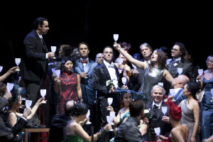 “ E’ la scena del brindisi: a destra Sonya Joncheva ( Violetta) e a sinistra Abdellah Lasri ( Alfredo). Assieme a loro, il coro della Staatsoper di Berlino (crediti fotografici: staatsoper-berlin@Bernd Uhlig)